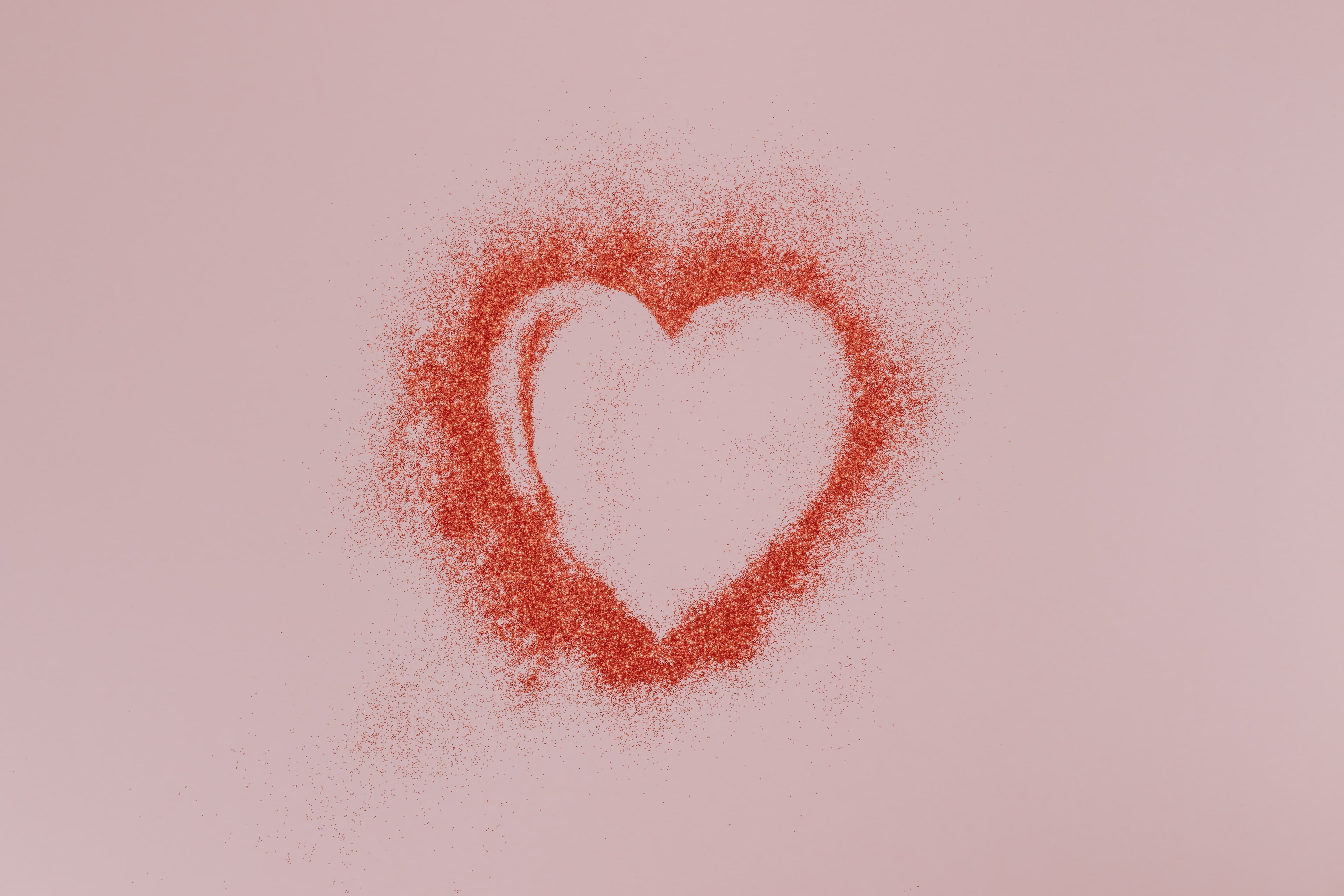 Love heart in red glitter on a pink background
