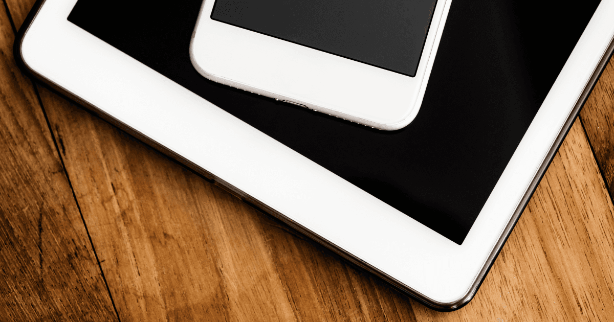 A white iPhone resting on a white iPad