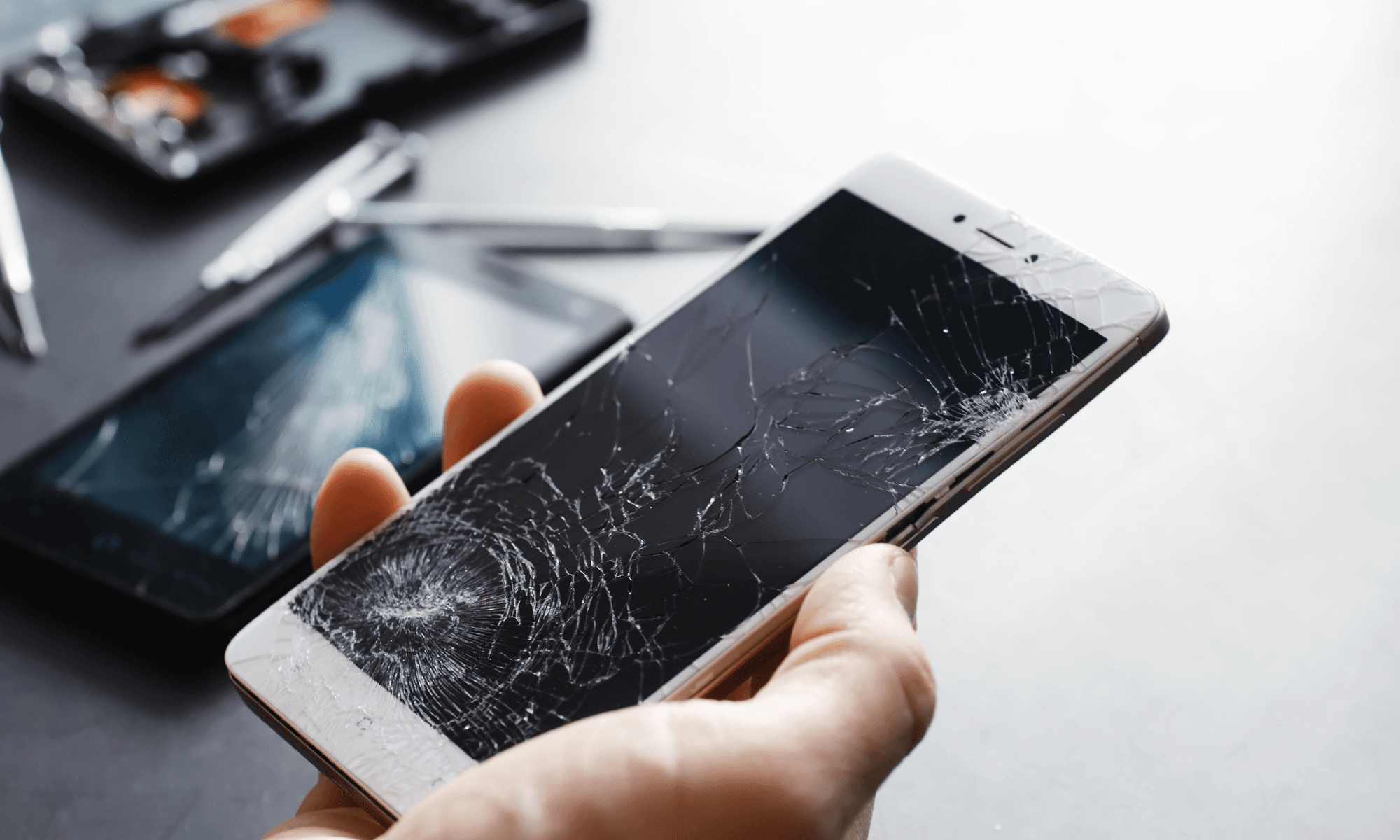 Close-up shot of a person's hand holding a a broken phone.