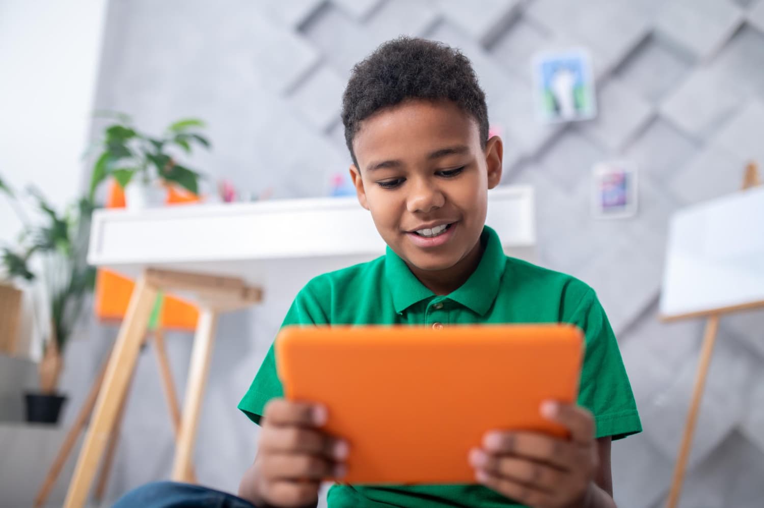 Dark-skinned boy looking at tablet with interest