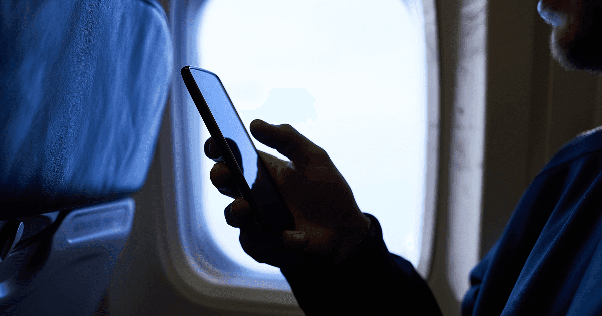 Man using his mobile phone on an aeroplane.